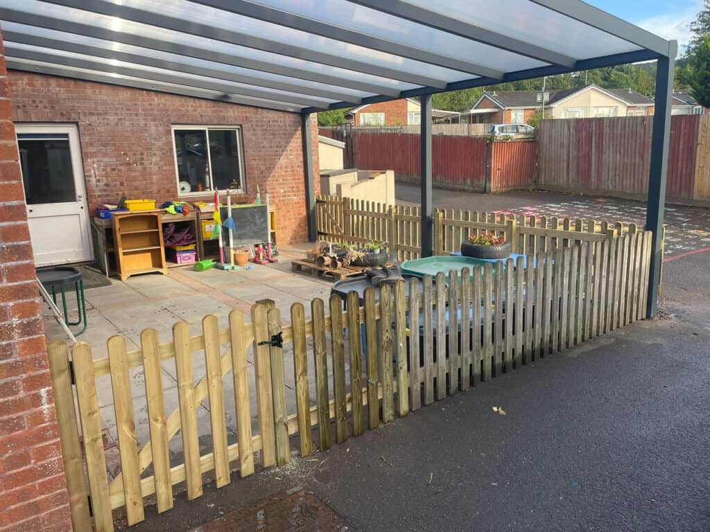 Child's outdoor play area with wooden fence and covered patio in Devon.