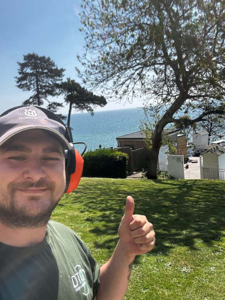 Man with headphones giving thumbs up near the coast in Devon.