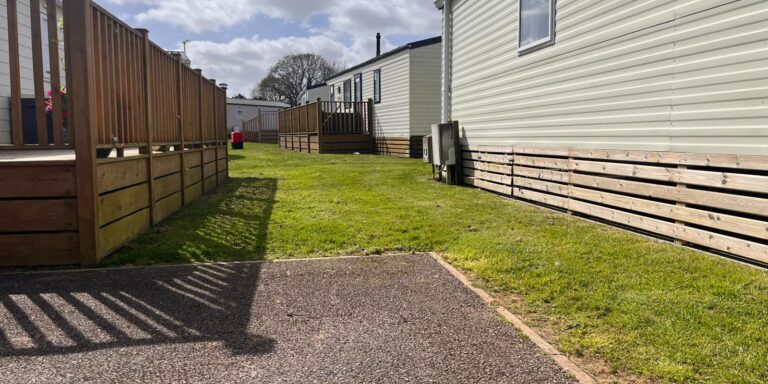 Well-maintained backyard with lawn, fence, and mobile home in Devon, UK.