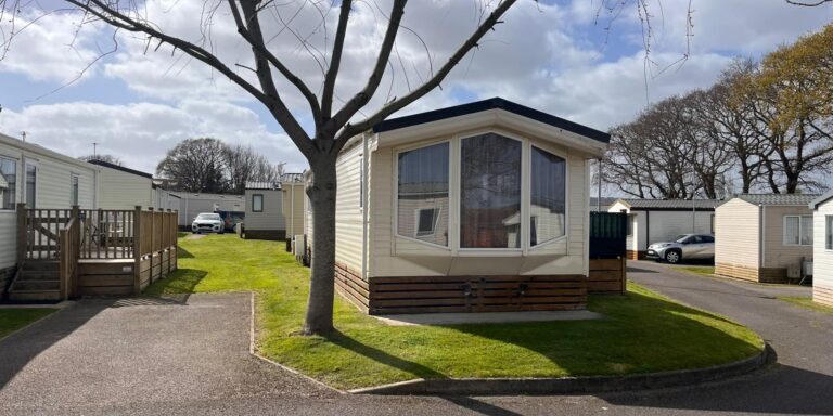 Mobile home with a tree in a caravan park in Devon, UK.