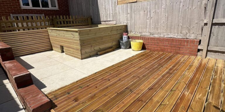 New wooden decking and raised garden beds in a residential backyard.