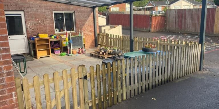 Child's outdoor play area with wooden fence and covered patio in Devon.